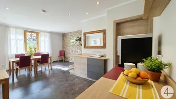Heller Essbereich mit Holztisch, roten Stühlen und einer dekorativen Steinwand.