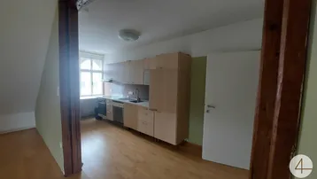 Funktionale Küche mit hellen Holzschränken, Einbaugeräten und Holzboden in einem Dachgeschossbereich.