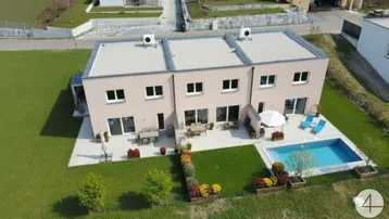 Moderne Reihenhäuser mit Flachdach, privaten Terrassen und einem Swimmingpool im Gartenbereich.