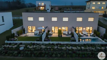 Moderne Reihenhäuser mit privaten Gärten, Terrassen und einem Pool bei Dämmerung.