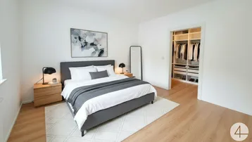Helles Schlafzimmer mit modernem Bett, Holzboden und direktem Zugang zu einem begehbaren Kleiderschrank.