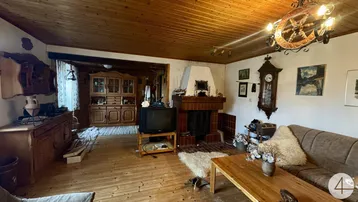 Gemütliches Wohnzimmer im Landhausstil mit Holzboden, Holzdecke und einem traditionellen Kamin.