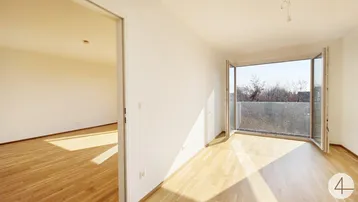 Heller Wohnbereich mit Parkettboden und Zugang zu einem französischen Balkon, ideal für Sonnenlicht.