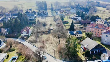 Luftaufnahme eines unbebauten Grundstücks in ländlicher Umgebung mit umliegenden Häusern und viel Grün.