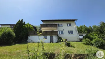 Rückseite des Hauses mit Balkonen und einem weitläufigen Gartenbereich mit Blick ins Grüne.