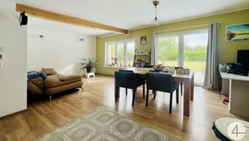 Heller offener Wohn- und Essbereich mit Holzbalken, Parkettboden und Zugang zum Garten.