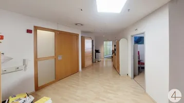 Heller Flur mit Holzfußboden und Oberlicht, der zu verschiedenen Büroräumen führt.