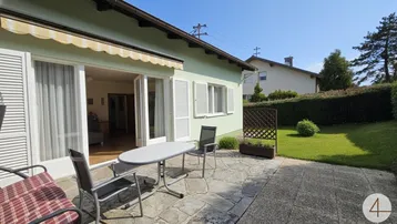 Sonnige Terrasse mit Gartenmöbeln und direktem Zugang zum gepflegten Rasenbereich des Gartens.