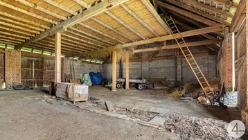 Geräumiger Innenbereich einer Scheune mit Holzbalken und viel Stauraum.