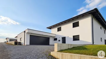 Modernes Einfamilienhaus mit weißer Fassade, dunklen Fensterläden und integrierter Garage.