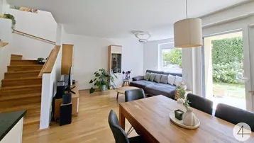 Helles Wohn- und Esszimmer mit Holzboden, Treppe und Zugang zur Terrasse.