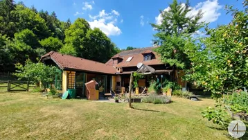 Großzügiges Anwesen mit Haupthaus, Gartenbereich und umgebender Naturlandschaft unter blauem Himmel.
