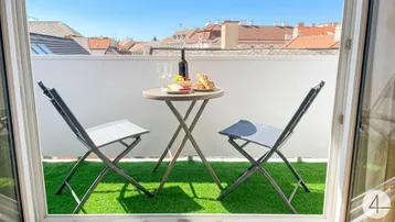Gemütlicher Balkon mit Kunstrasen, kleinem Tisch und Stühlen, ideal für entspannte Stunden im Freien.