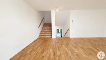 Heller Eingangsbereich mit Holztreppe und Parkettboden, der zu weiteren Räumen führt.
