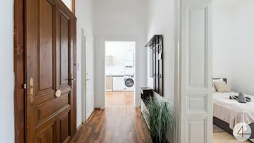 Heller Flur mit Holzboden und Garderobe, der zu Küche und Schlafzimmer führt.