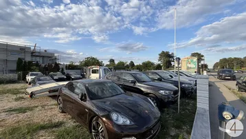 Außenansicht eines Grundstücks mit geparkten Autos auf Gras und einem Gebäude im Bau.
