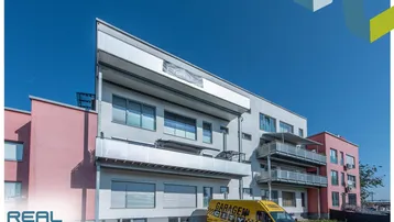 Modernes Mehrfamilienhaus mit Balkonen und einer markanten Architektur unter blauem Himmel.