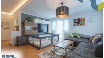 Gemütliches Wohnzimmer mit großem Ecksofa, Holzboden und moderner Deckenbeleuchtung.
