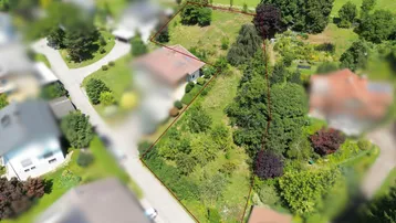 Luftaufnahme eines Grundstücks mit bestehendem Haus, umgeben von Grünflächen und Wegen.