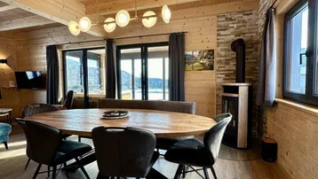 Geräumiger Essbereich mit großem Holztisch, modernen Stühlen und Kaminofen.
