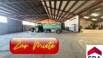 Geräumige Lagerhalle mit hoher Decke und Betonboden, ideal für landwirtschaftliche Fahrzeuge und Geräte.