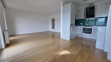 Heller Wohnbereich mit Parkettboden und integrierter Küche, ideal für offenes Wohnen.