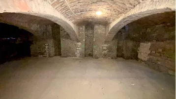 Historischer Kellerraum mit beeindruckendem Ziegelgewölbe und robustem Betonboden, der eine einzigartige Atmosphäre schafft.