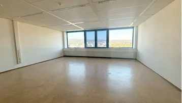 Geräumiges, leeres Büro mit großen Fenstern, die einen weiten Blick über die Landschaft bieten.