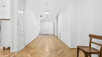 Langer Flur mit Fischgrätparkett und hohen weißen Türen, der zu weiteren Räumen führt.