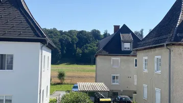 Blick auf eine weite grüne Landschaft mit Feldern und Wäldern von einem Gebäude aus.