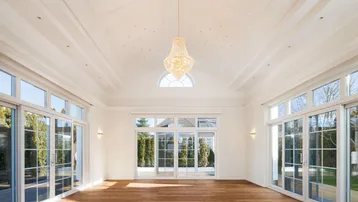 Helles, geräumiges Zimmer mit hohen Decken, Holzboden und großen Fenstern zum Garten.