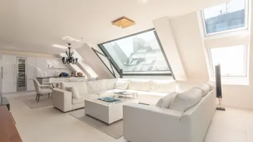 Helles, offenes Wohn- und Esszimmer mit integrierter Küche, großen Dachfenstern und modernen Möbeln.