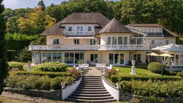 Herrschaftliche Villa mit weitläufigem Garten, Terrasse und Blick auf die grüne Umgebung.