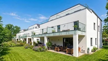 Reihenhäuser mit Gärten, Terrassen und Balkonen in einer grünen Umgebung.