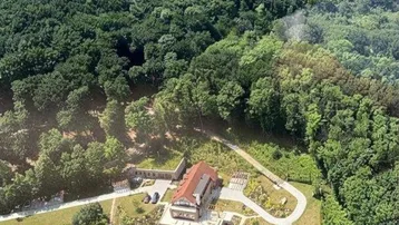 Luftaufnahme des Anwesens mit großem Haus, Pool und weitläufigen Grünflächen in bergiger Landschaft.