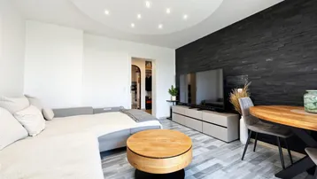 Modernes Wohn-Esszimmer mit dunkler Schieferwand, Parkettboden und integrierten Deckenleuchten.