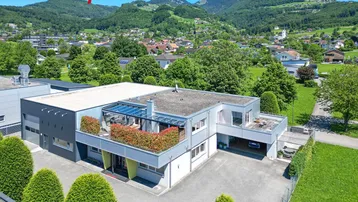 Luftaufnahme eines modernen Gebäudekomplexes mit Flachdach und begrünten Terrassen in ländlicher Umgebung.