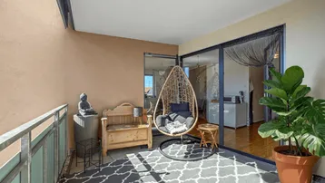 Gemütlicher Balkon mit Hängesessel, Holzbank und Pflanzen, ideal zum Entspannen im Freien.