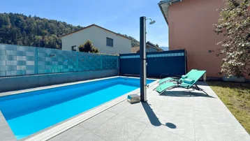 Privater Poolbereich mit Außendusche, Liegestühlen und Blick auf die Berge.