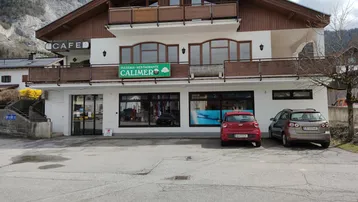 Gebäude mit Pizzeria-Restaurant im Erdgeschoss und Wohnungen darüber, umgeben von Bergen.