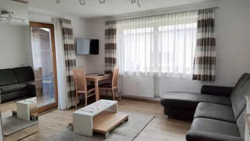 Gemütlicher Wohn-Essbereich mit bequemer Eckcouch, Esstisch und Zugang zum Balkon.