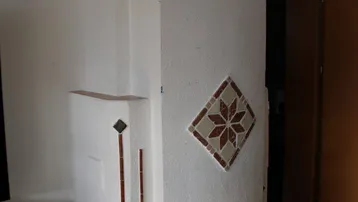 Traditioneller Kachelofen im Wohnbereich mit dekorativen Fliesen und weißem Putz.