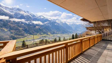 Große Terrasse mit Holzbalkongeländer und atemberaubendem Blick auf die schneebedeckten Berge und das Tal.