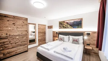 Gemütliches Schlafzimmer im alpinen Stil mit Doppelbett, Holzmöbeln und moderner Dekoration.