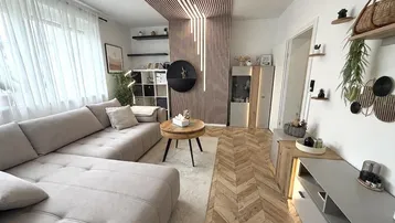 Modernes Wohnzimmer mit beigem Ecksofa, Holzlamellenwand und Fischgrätparkettboden.