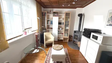 Helles Wohnzimmer mit Holzdecke, Kaminofen und Holzboden, ideal für gemütliche Abende.
