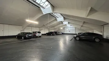 Geräumige Tiefgarage mit mehreren Stellplätzen und Oberlichtern, die natürliches Licht hereinlassen.