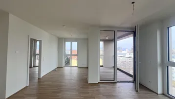Helles Wohnzimmer mit Parkettboden und Zugang zu einem Balkon mit Stadtblick.