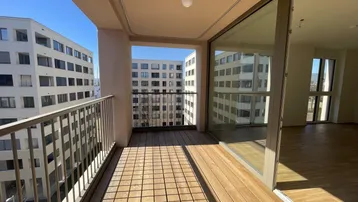 Geräumiger Balkon mit Holzboden und Blick auf die umliegenden Gebäude, ideal für sonnige Tage.