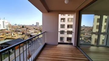 Geräumiger Balkon mit Holzboden und Blick auf die Stadt und umliegende Gärten.